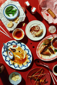 A table top view of a chineese celebratory table, half eaten over a red tablecloth